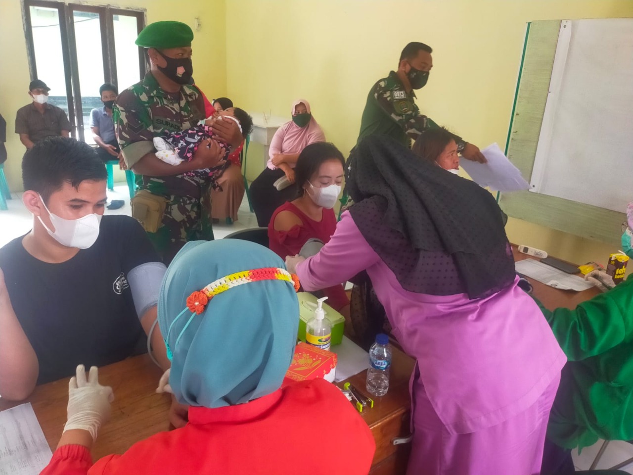 Dengan Sigap, Anggota TNI Ini Gendong Bayi Peserta Vaksin